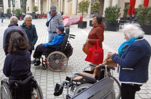 Eine Gruppe von Menschen, darunter einige im Rollstuhl, trifft sich im Humboldtforum für eine Selbsthilfegruppe.