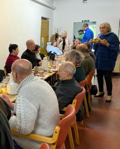 Eine Gruppe von Menschen sitzt an einem langen Tisch und genießt ein gemeinsames Essen.