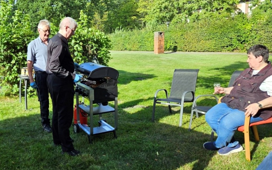 Mann am Grill mit zwei weiteren Personen