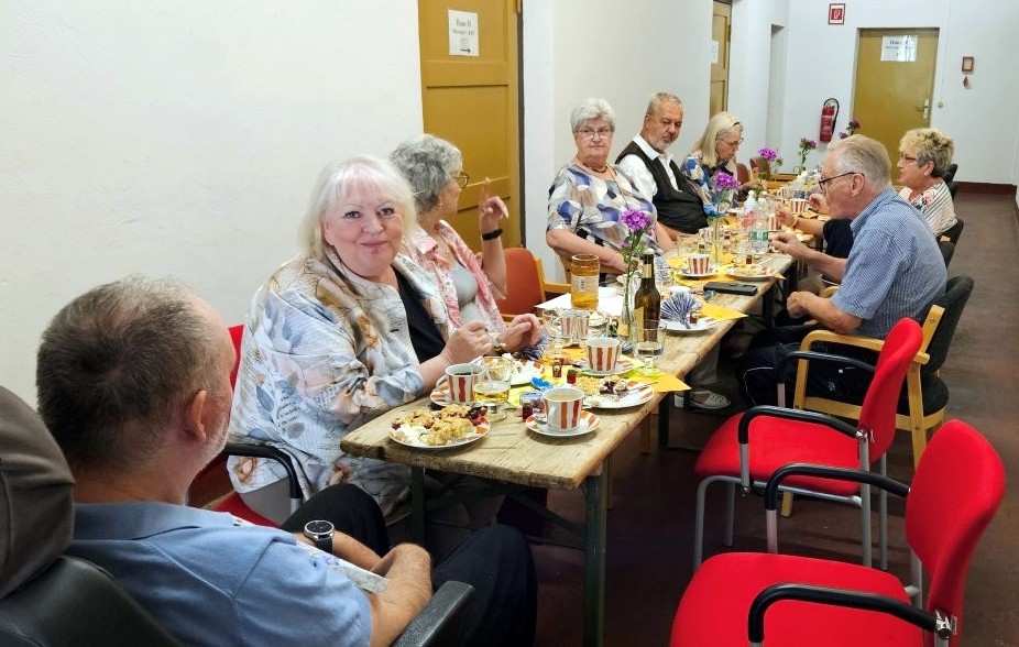 Tafel mit Lebensmitteln und Getränken, an der mehrere Personen sitzen