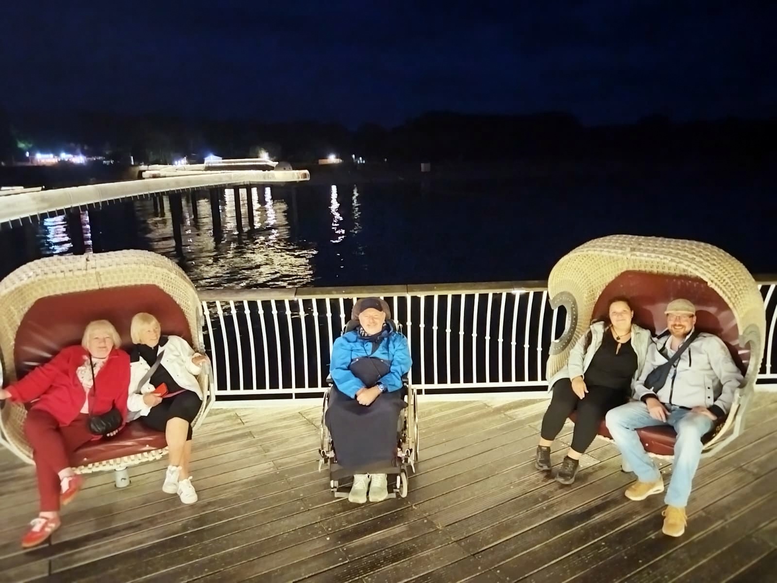 Personen auf Sesseln auf der Seebrücke bei Nacht